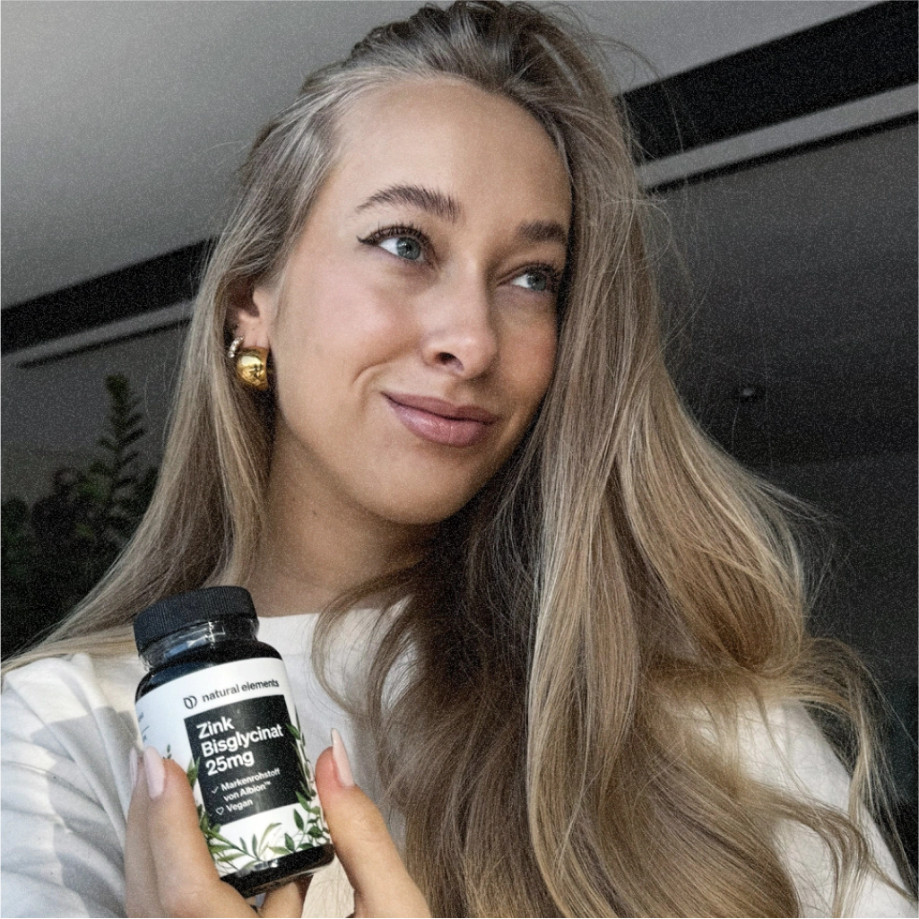 A woman holds up a bottle of Vitamin C, which is derived from natural elements.