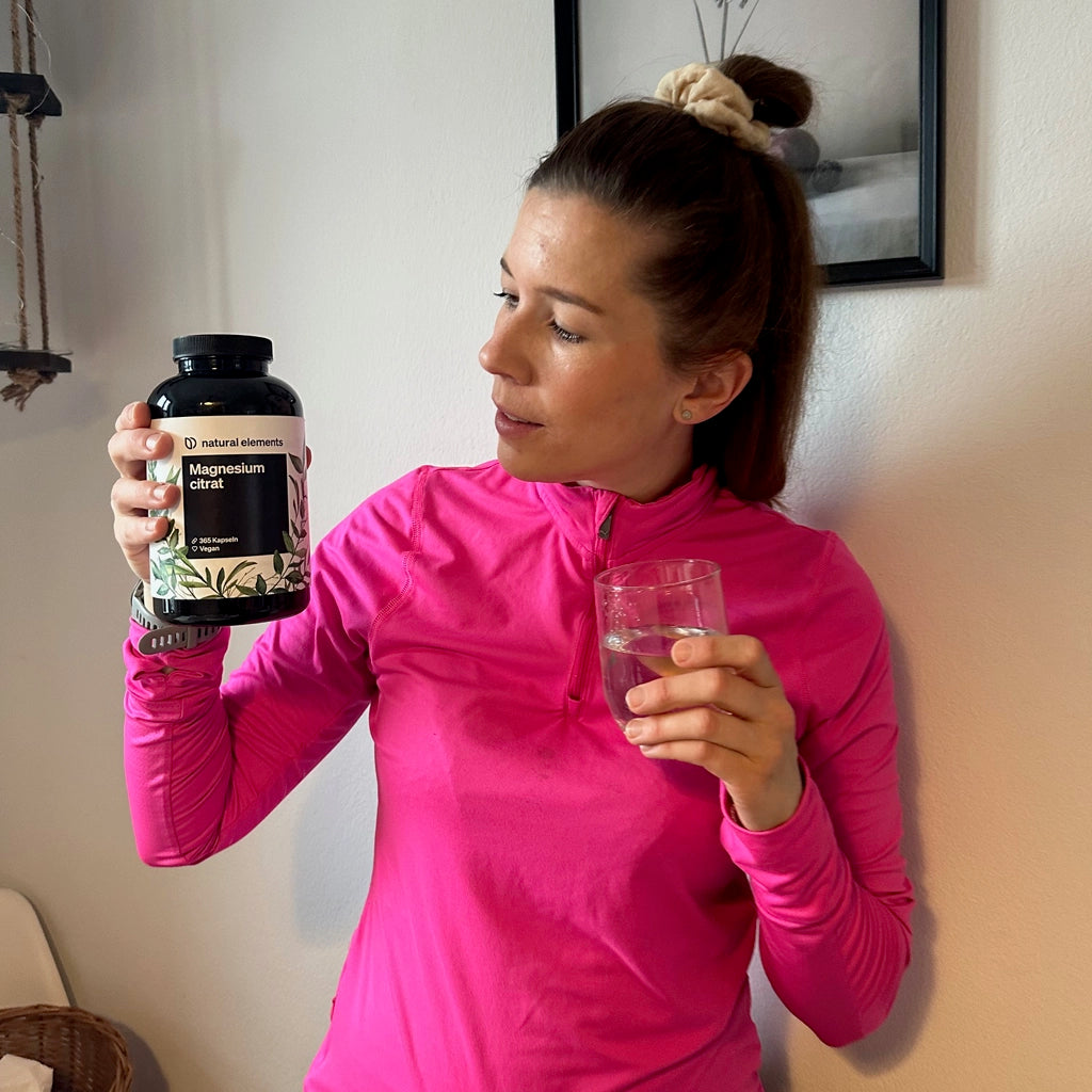 A woman holds a bottle of water and natural food supplements in her hand.